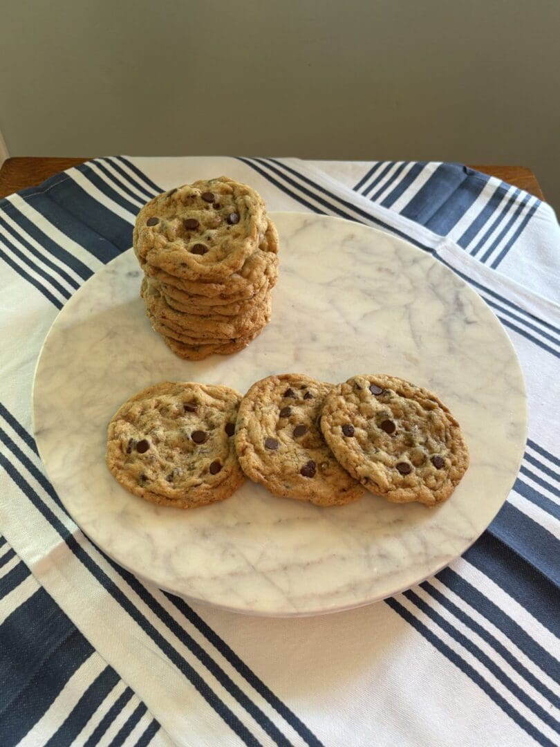 Stack of toasted English muffins on a marble board beside sliced halves.